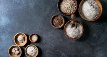 Farine e mix in ciotole di legno: farina integrale, lievito, semi di lino. Ingredienti per pane e pizza.