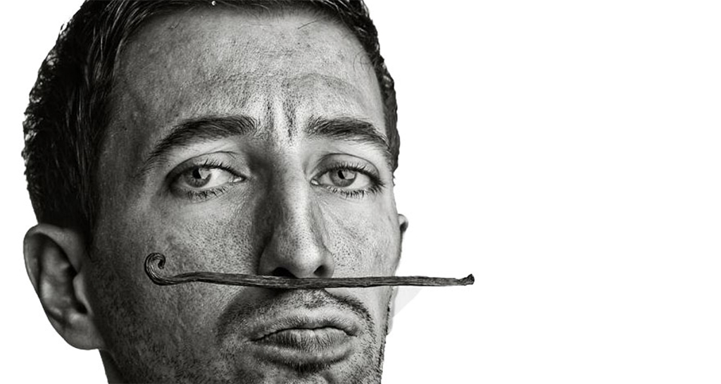 Ritratto in bianco e nero di Vito Cortese con baccello di vaniglia come baffi.