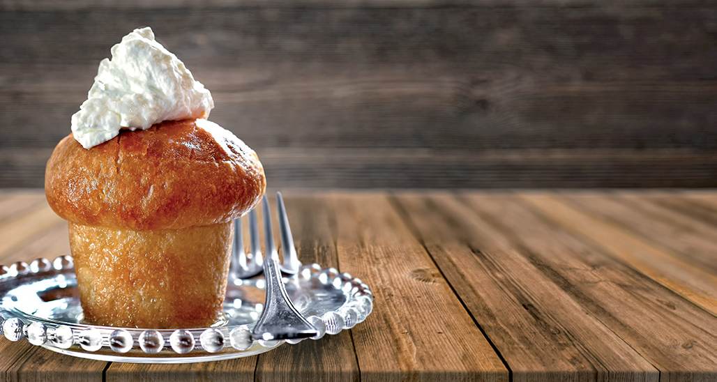 Babà al rum con panna su piatto decorato. Dolce napoletano tradizionale, dessert alcolico.