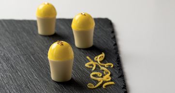 Biancomangiare servito: dolci monoporzione con glassa gialla e scorza di limone su ardesia. Dessert elegante.