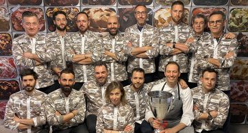 Team di gelatieri italiani con divisa mimetica, coppa del vincitore. Gelato artigianale, eccellenza italiana.