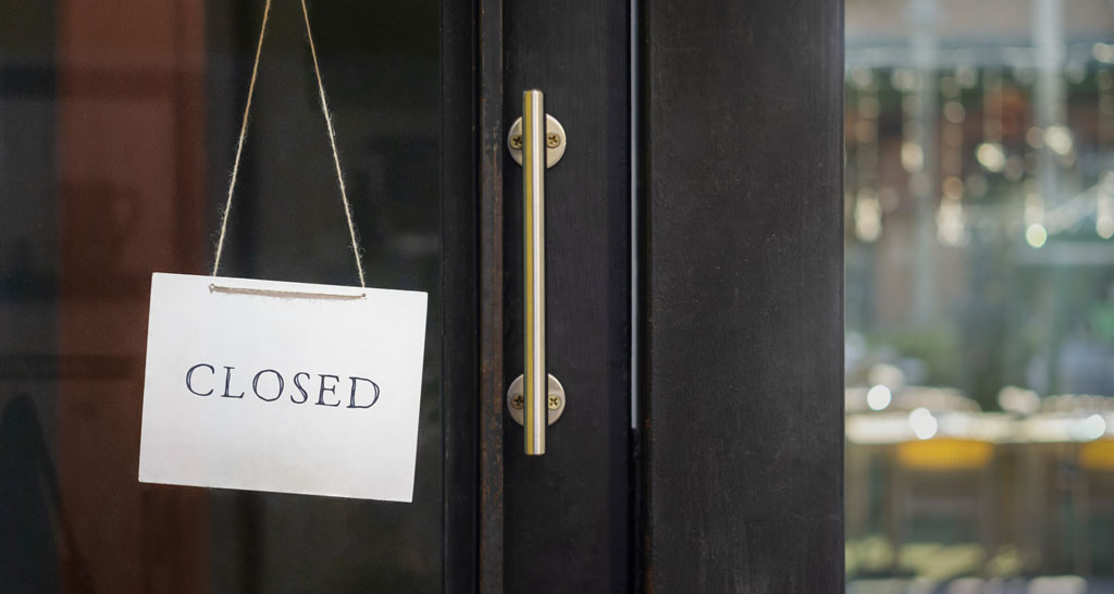Chiuso. Cartello CLOSED su porta di ristorante. Attività commerciale chiusa. Serranda abbassata.