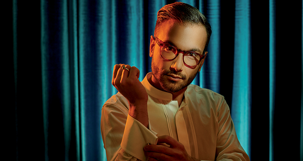 Uomo con occhiali rossi e camicia bianca. Sfondo blu. Moda uomo, stile elegante.