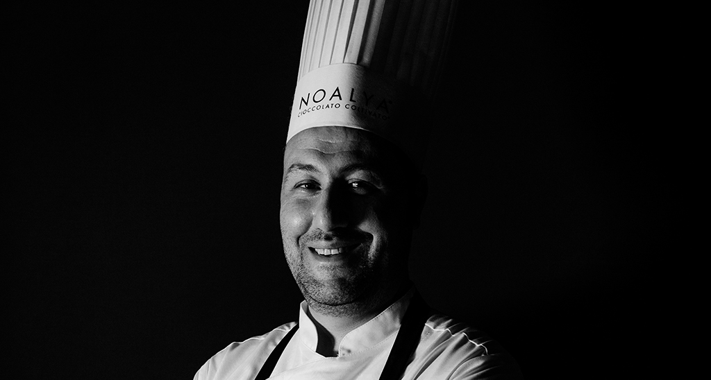 Chef cioccolatiere sorridente in bianco e nero con cappello da cuoco.