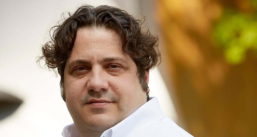 Ritratto di Gianluca Fusto, famoso pasticcere e cioccolatiere italiano. Chef con capelli ricci.