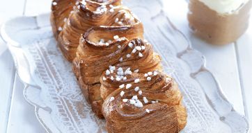 Treccia di pasta sfoglia con granella di zucchero su vassoio. Dolce da forno, colazione.
