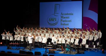 Gruppo di Maestri Pasticceri Italiani AMPI festeggiano sul palco con calici. Evento, pasticceria italiana.