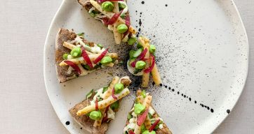 Pizza gourmet con asparagi, fave e cipolle rosse caramellate su piatto decorato. Ricetta primaverile.