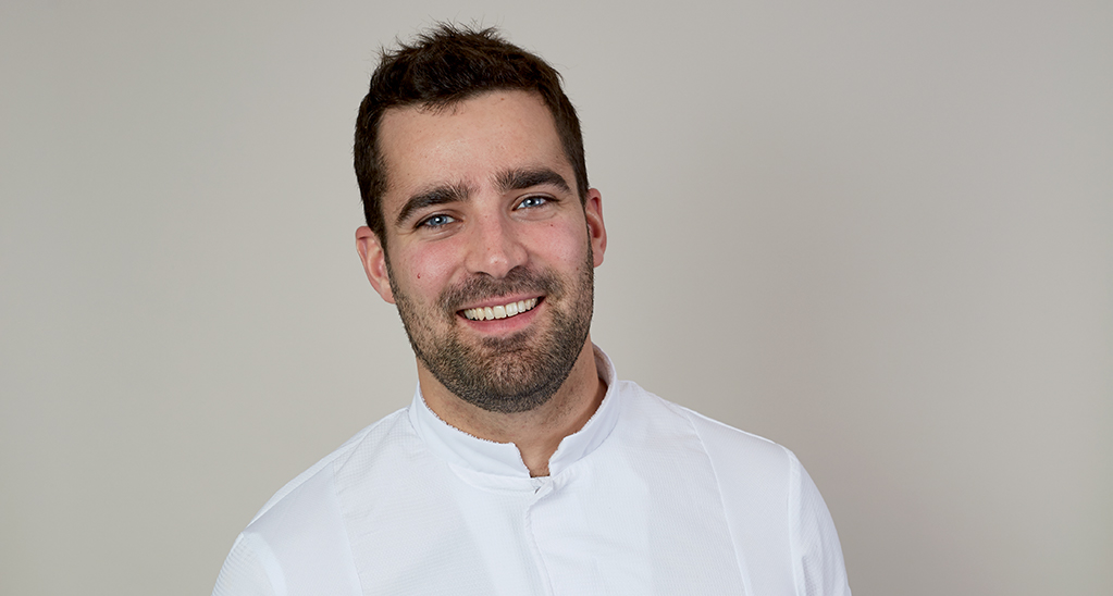 Ritratto di Guillaume, uomo sorridente con occhi azzurri e barba. Professionista in camicia bianca.