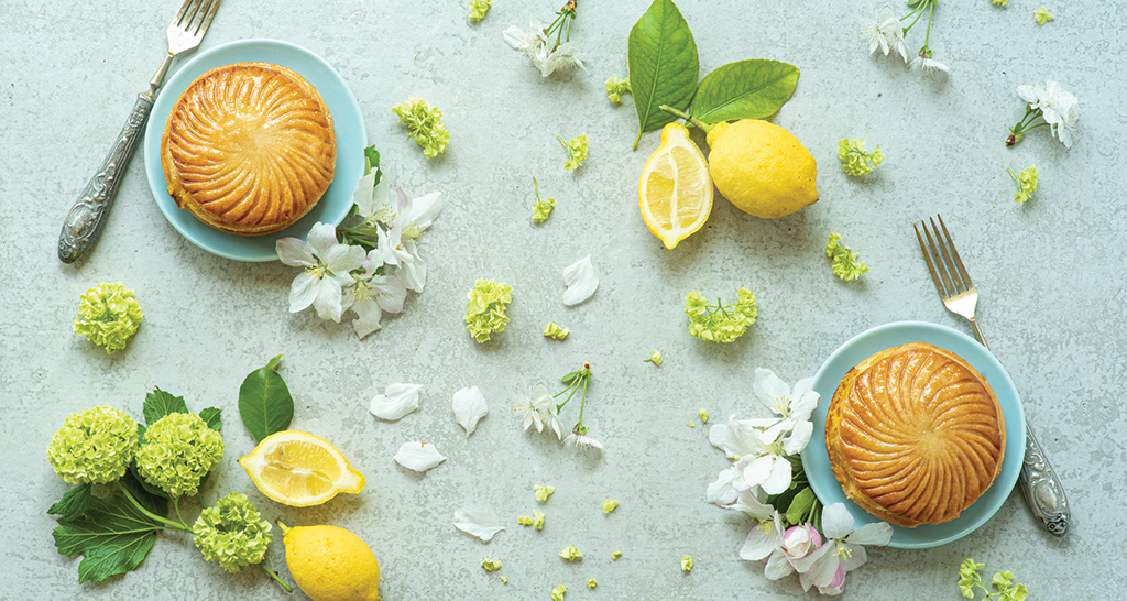 Due tortini, limoni e fiori. Dolci da forno su piatti azzurri, forchette vintage. Dessert primaverili.