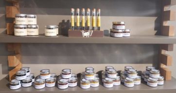 Scaffale con prodotti tipici italiani: marmellate, miele, nocciole, mandorle e scorze di agrumi. Prodotti artigianali.