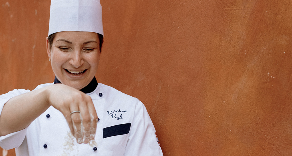Chef Valentina Vogli sorride mentre cucina. Cucina italiana, chef donna.