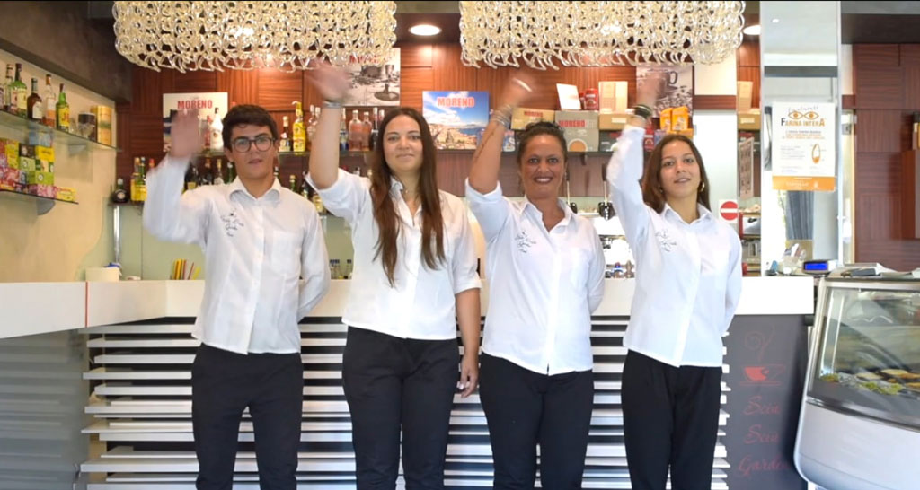 Staff del bar Sciu Sciu saluta. Team sorridente in divisa, accoglienza calorosa. Bar, caffetteria, cordialità.