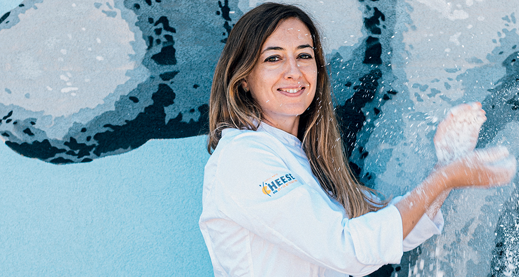 Chef Chiara Zogno, esperta casearia. Donna sorridente in divisa da cuoco. Produttrice di formaggio artigianale.