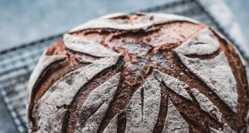 Pane artigianale integrale. Pagnotta di pane scuro con crosta croccante. Lievitazione naturale.