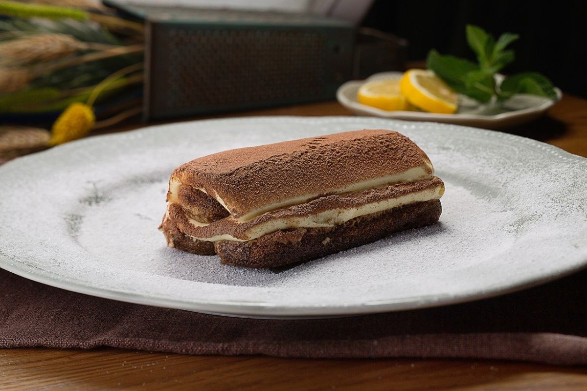 Tiramisù classico su piatto bianco. Dessert italiano con cacao.