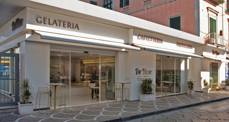 Gelateria e pasticceria italiana De Vivo. Facciata bianca, tavolini esterni. Ottimo gelato artigianale e dolci.
