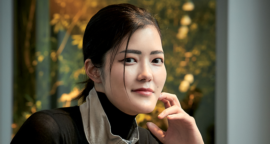 Ritratto ufficiale di Natsuko, donna asiatica con capelli scuri. Sguardo diretto e sfondo naturale.