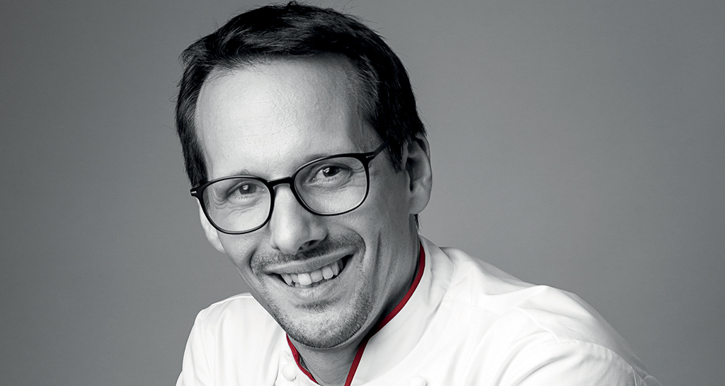 Ritratto di Franco Ascari, chef sorridente con occhiali. Cucina italiana.