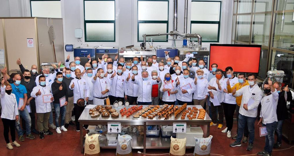 Gruppo di panettieri con pane artigianale. Corso di panificazione, prodotti da forno, farine.