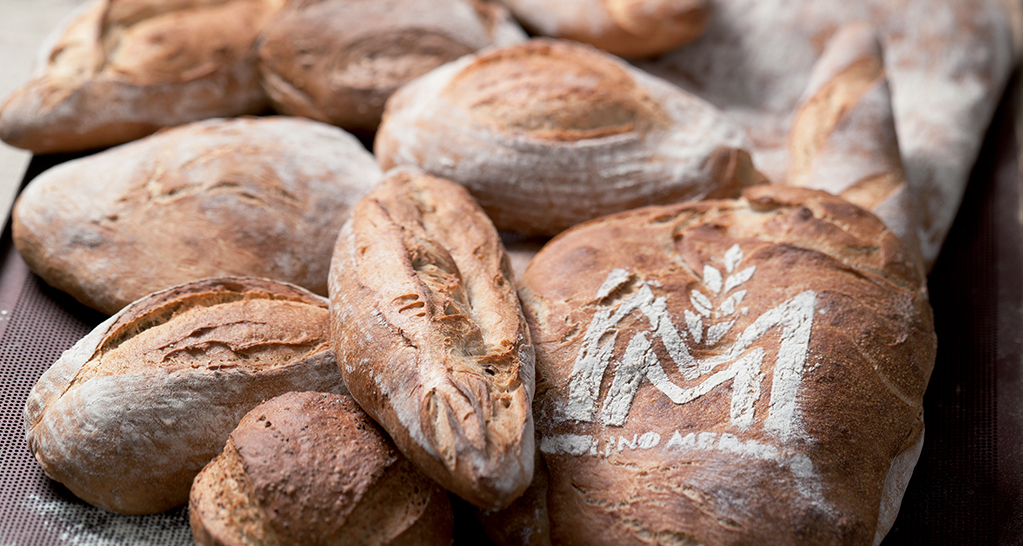 Pane artigianale di Molino Merano. Pagnotte fresche con logo, crosta dorata. Panificio di alta qualità.