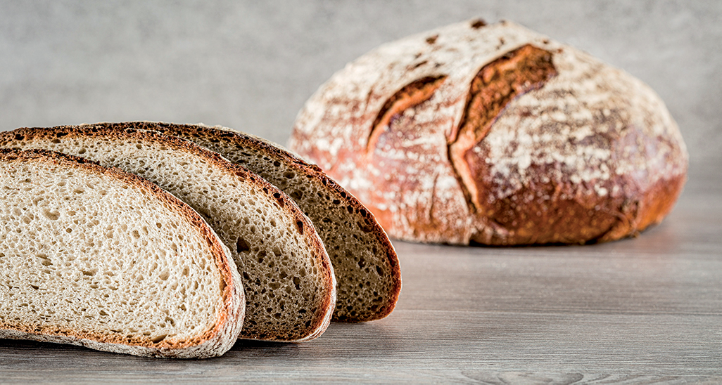 Pane di segale artigianale. Fette di pane integrale su tavolo di legno. Panificazione tradizionale.