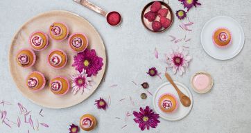 Mini cupcake e fiori. Dolcetti con glassa rosa e lamponi. Pasticceria artigianale, dessert elegante.