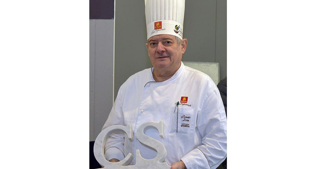 Chef pasticcere con cappello e divisa bianca, premio CS. Cucina italiana d'eccellenza.