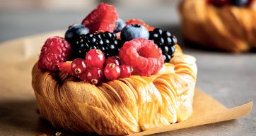 Croissant con frutti di bosco freschi. Pasticceria dolce con lamponi, more e mirtilli.