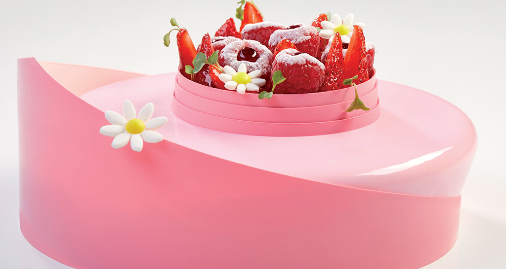 Cheesecake rosa con fragole, lamponi e decorazioni floreali. Dolce delizioso.