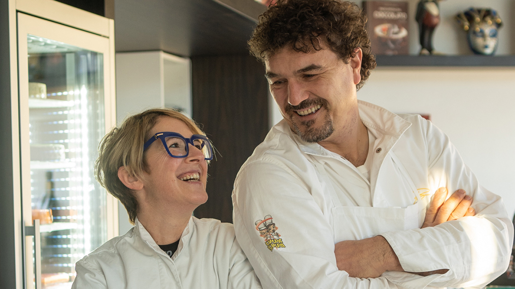 Pasticceri sorridenti in laboratorio. Dolci artigianali, cioccolato di qualità. Coppia di chef felici.