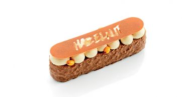 Dolce rettangolare Hazelnut: dessert al cioccolato e nocciole con crema e decorazione arancione.