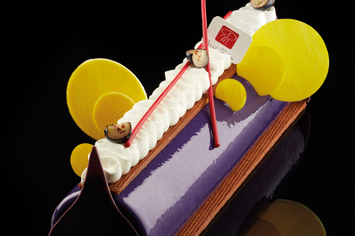 Dolce Sottobosco: dessert viola con panna, dischi gialli e decorazioni rosse. Pasticceria creativa.