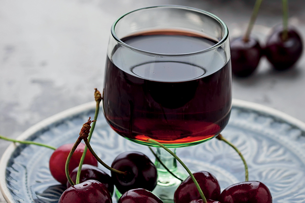 Aromi alcolici per pasticceria: bicchiere di liquore alla ciliegia con ciliegie fresche.
