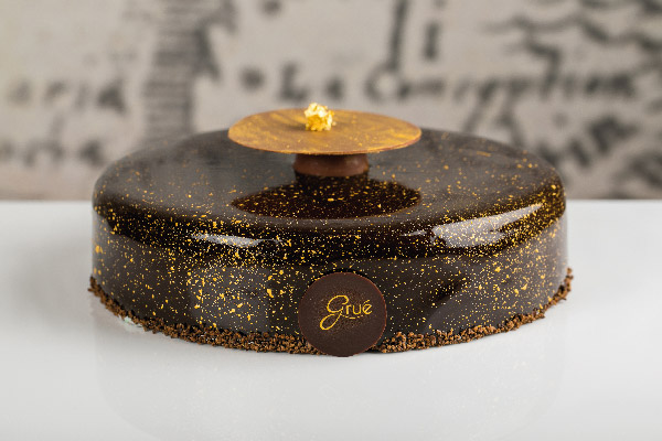 Torta Grué di Marta Boccanera: elegante dessert al cioccolato con glassa lucida e decorazioni dorate.