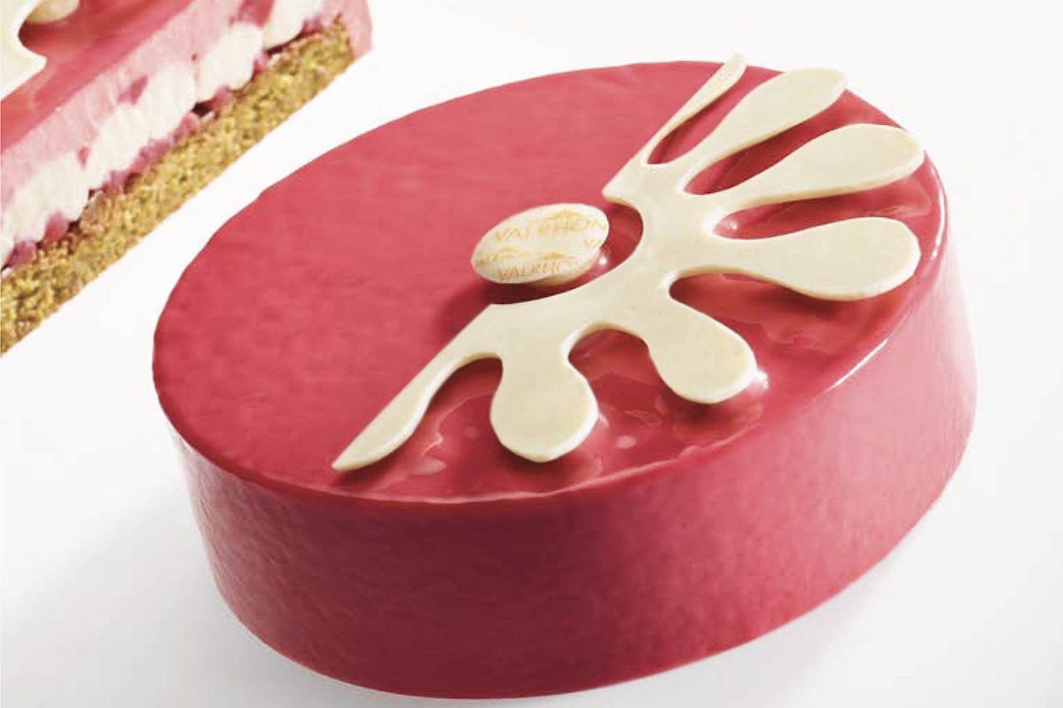 Torta Valrhona Paquerette per la Festa della Mamma. Dolce rosa con decorazione bianca.