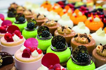 Assortimento di pasticceria mignon artigianale: dolci colorati e decorati con frutta fresca e cioccolato.