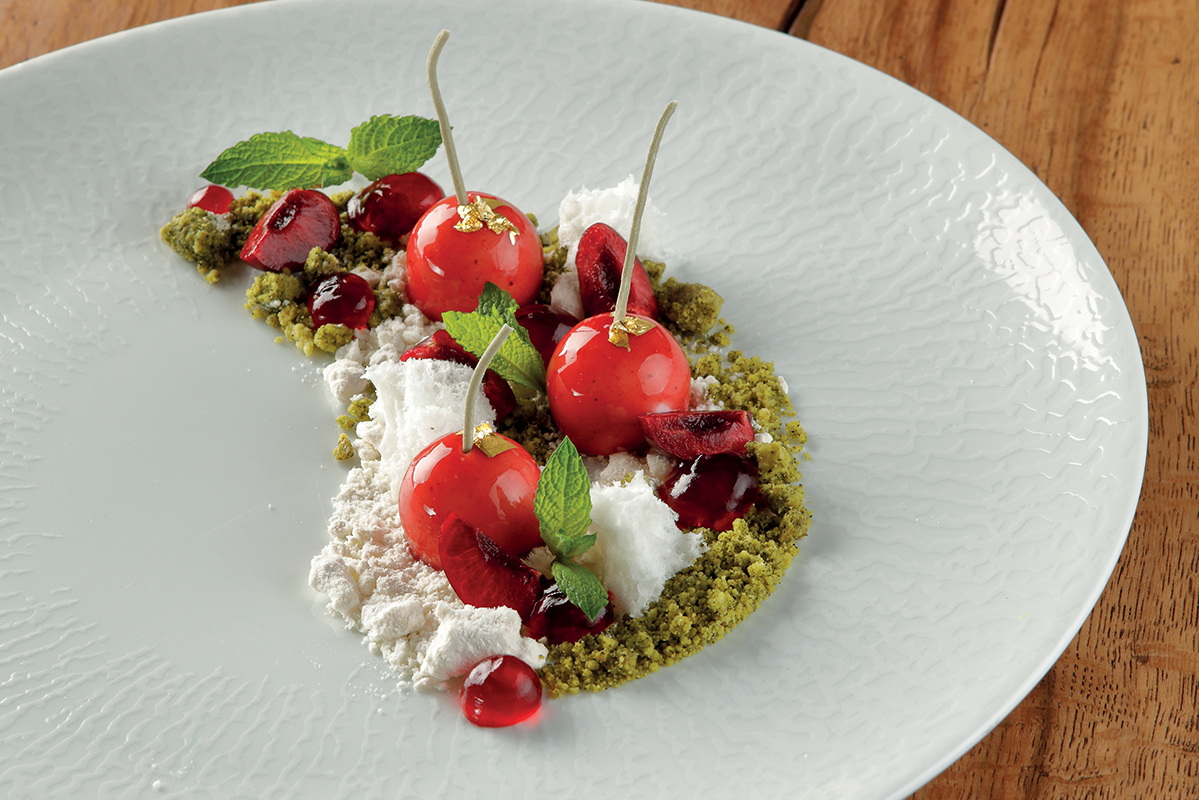 Ciliegia di Max Mascia: dessert gourmet con ciliegie, menta e crumble su piatto elegante.