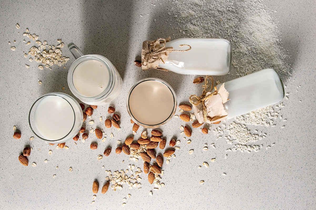 Bevande vegane: latte di mandorla, avena e riso in bottiglie e bicchieri.