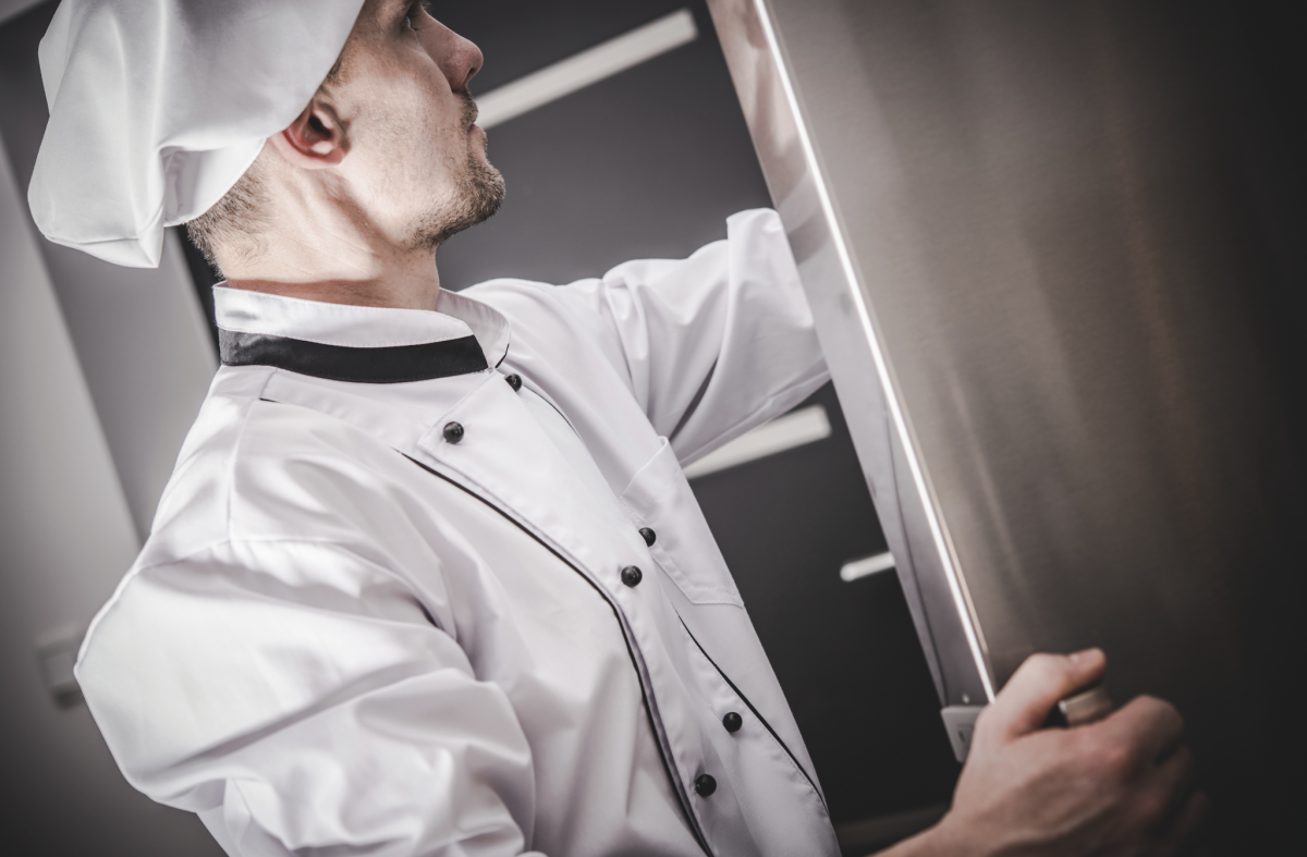 Chef professionista apre sistema del freddo. Frigorifero professionale.