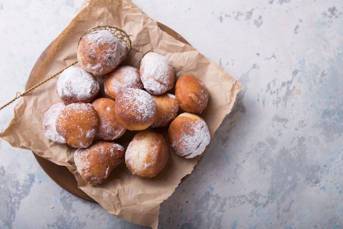 Bomboloni fritti con olio Senna Top, cosparsi di zucchero a velo. Dolci italiani.