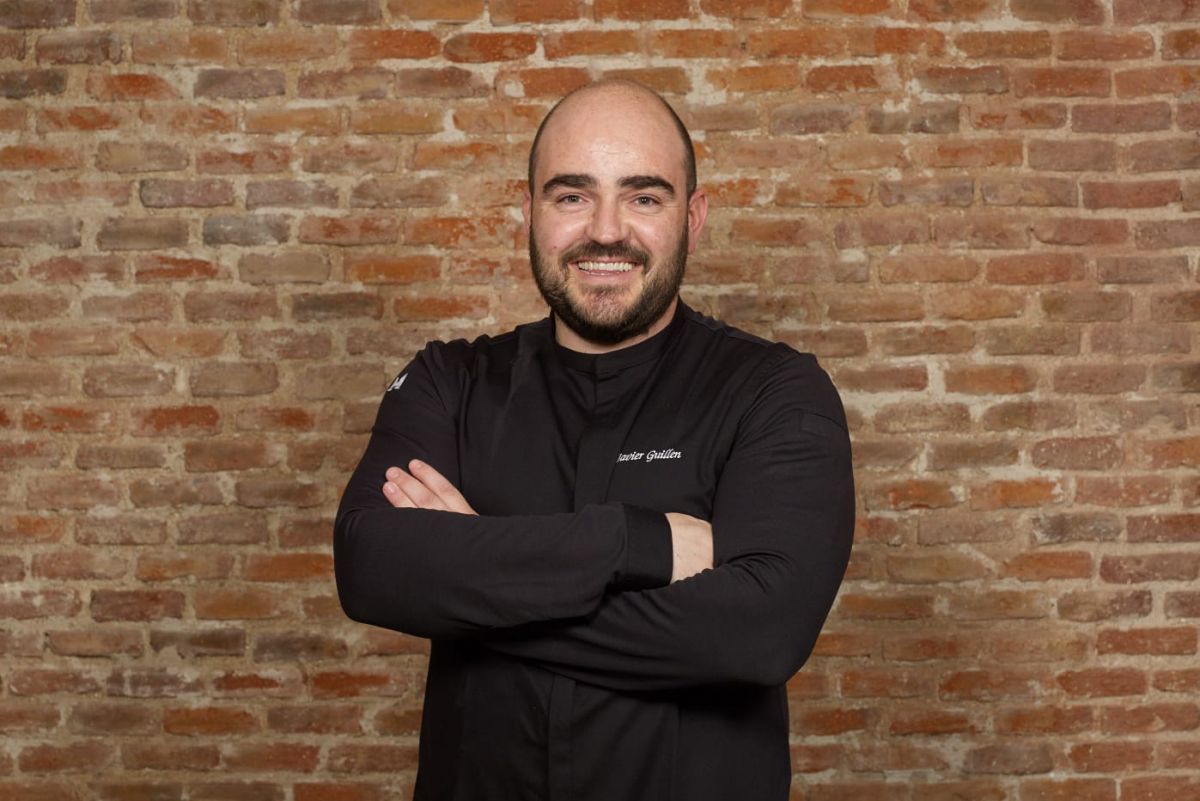 Chef Javier Guillen collabora con Valrhona. Ritratto dello chef su sfondo di mattoni.