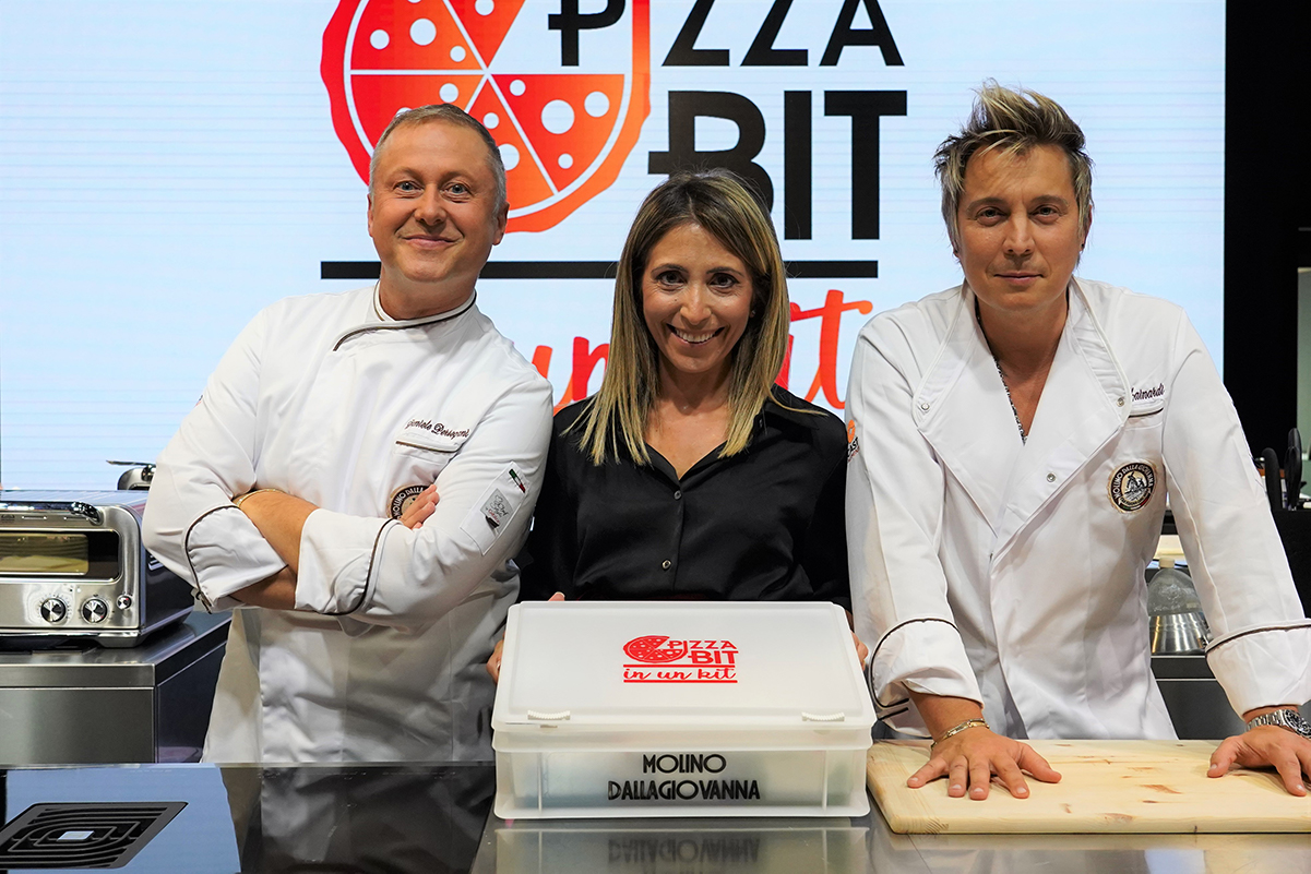 Team Pizza Bit Battle Molino Dallagiovanna con kit pizza. Chef e presentatrice sorridenti.