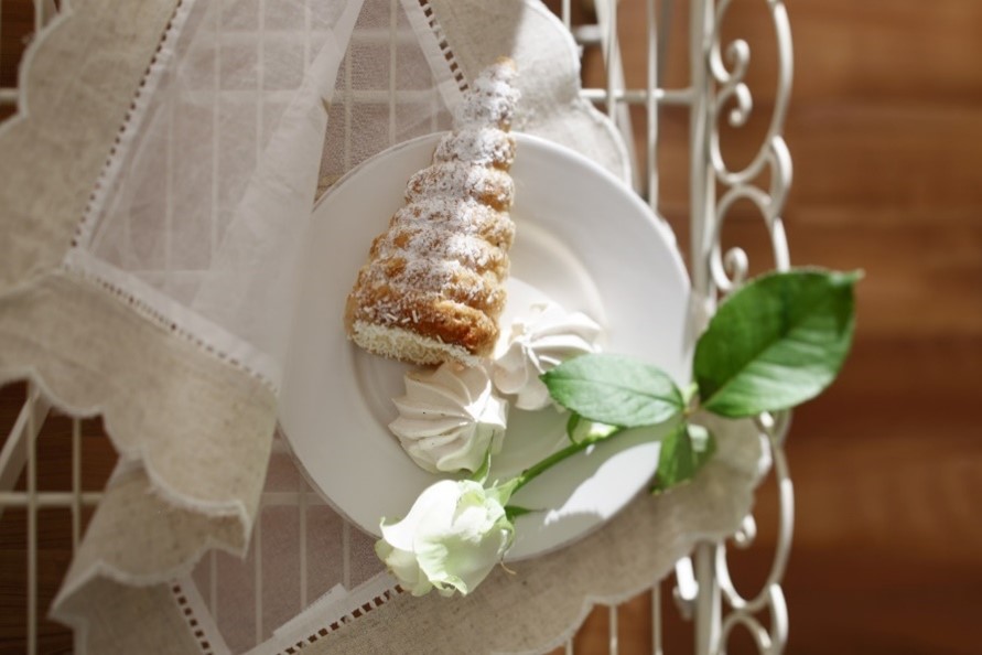 Dolce con burro tecnico Senna su piatto con meringhe e rosa bianca. Pasticceria artigianale.