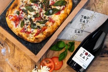 Pizza Top Eat Verona con pietra ollare, pomodoro, mozzarella e basilico. Bottiglia di vino rosso.