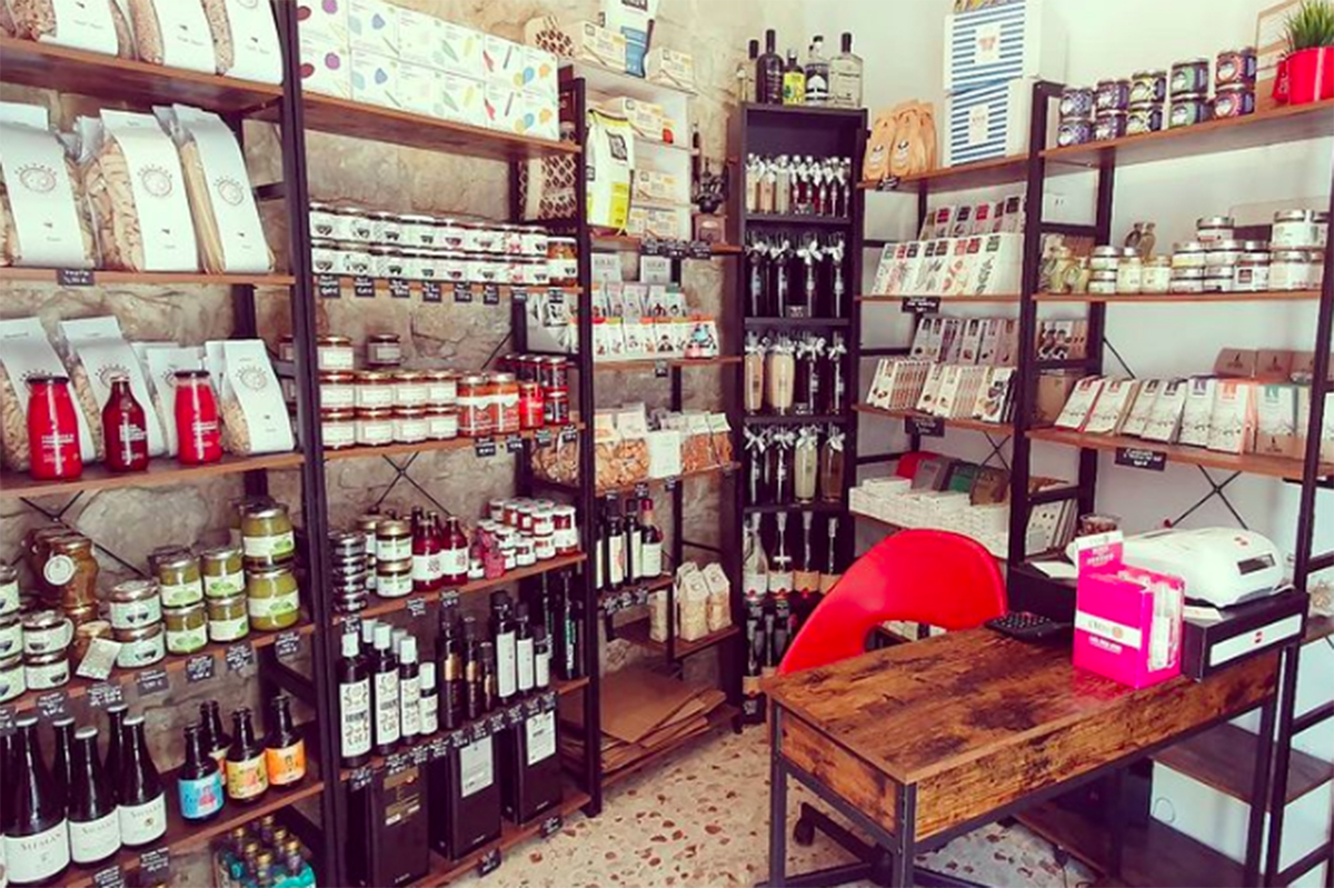 Interno bottega di Salvatore: scaffali con pasta, conserve, olio e vini siciliani. Prodotti tipici.