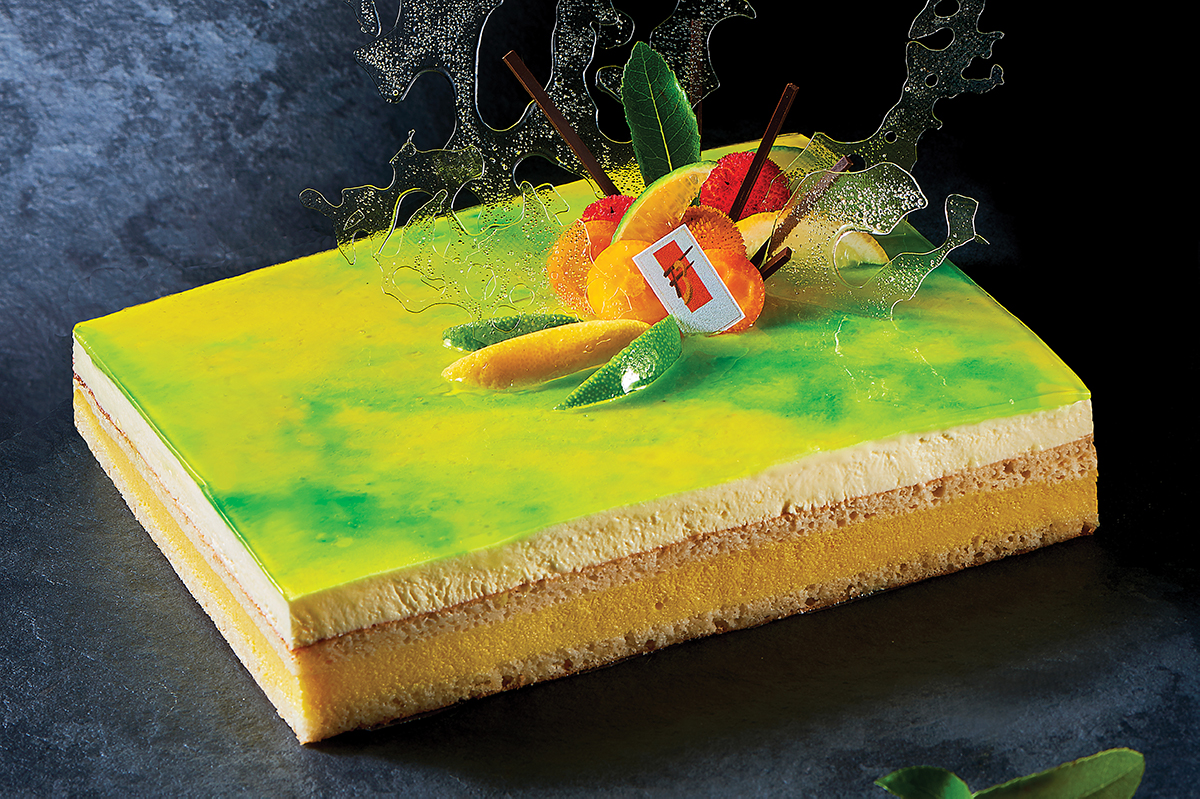 Dolce Riviera: torta di Frédéric Bourse con glassa verde, frutta fresca e decorazioni di zucchero. Pasticceria artigianale.