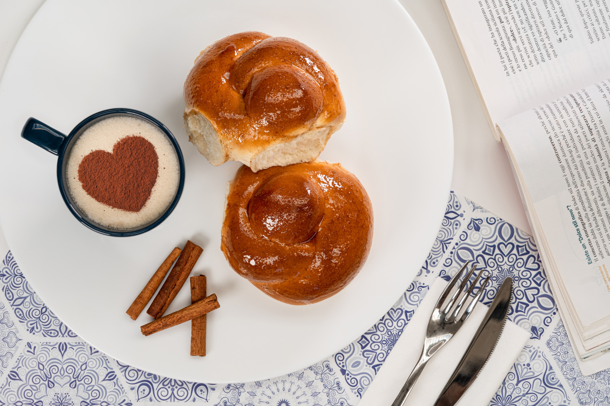 Colazione italiana: brioche soffice e cappuccino con cuore di cacao. Buongiorno!