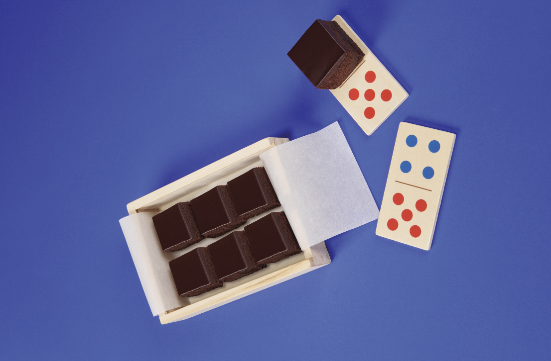 Brownie intense in scatola di legno con domino su sfondo blu.