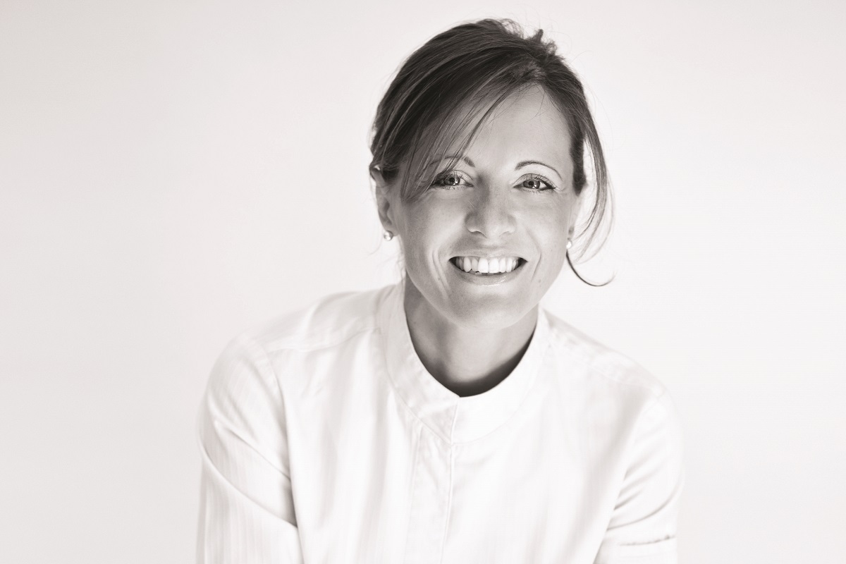 Ritratto di Claire Heitzler, chef pasticcera al servizio del gusto. Sorriso e professionalità in bianco e nero.